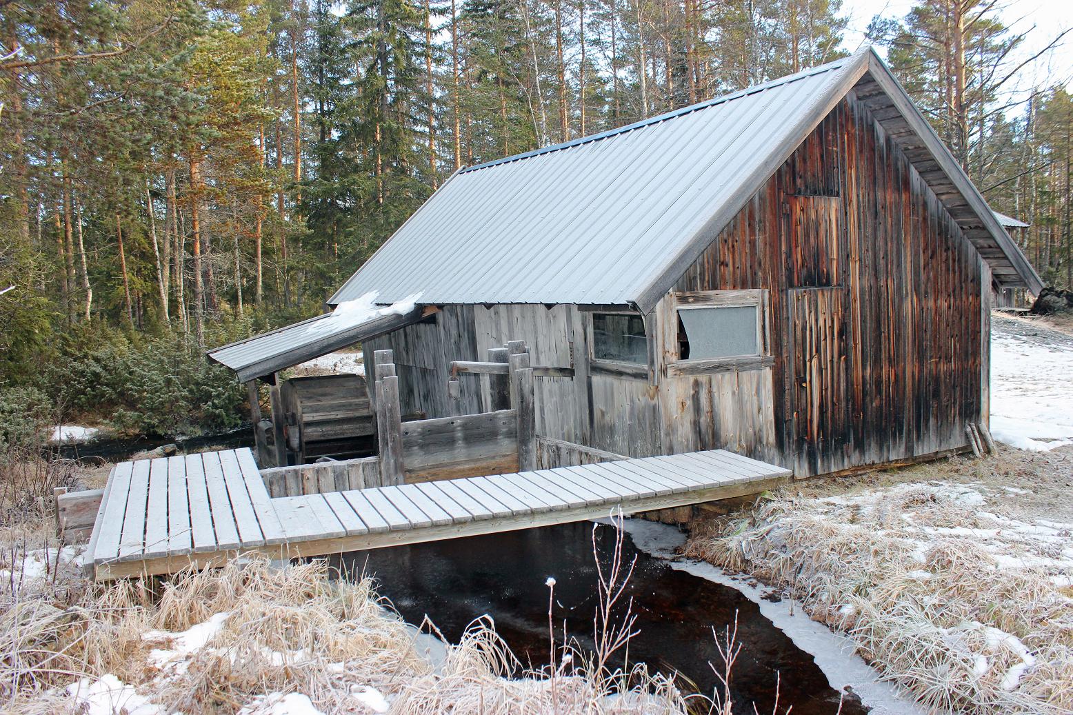 Historisk brynsåg av trä bredvid en å